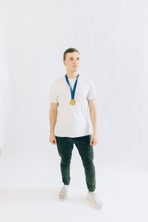 Man in White Crew Neck Shirt and Black Pants with a Medal