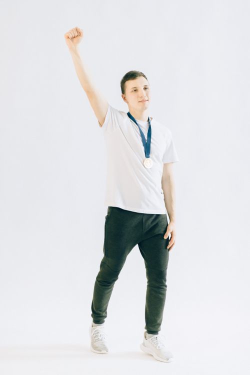 Free Energetic young athlete celebrating victory wearing a medal and raising a fist in triumph. Stock Photo