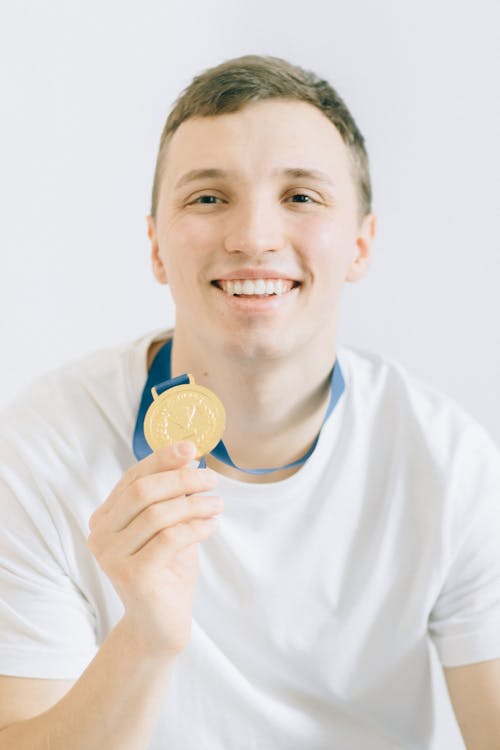 Smiling Boy in White Crew Neck Shirt Holding a Medal