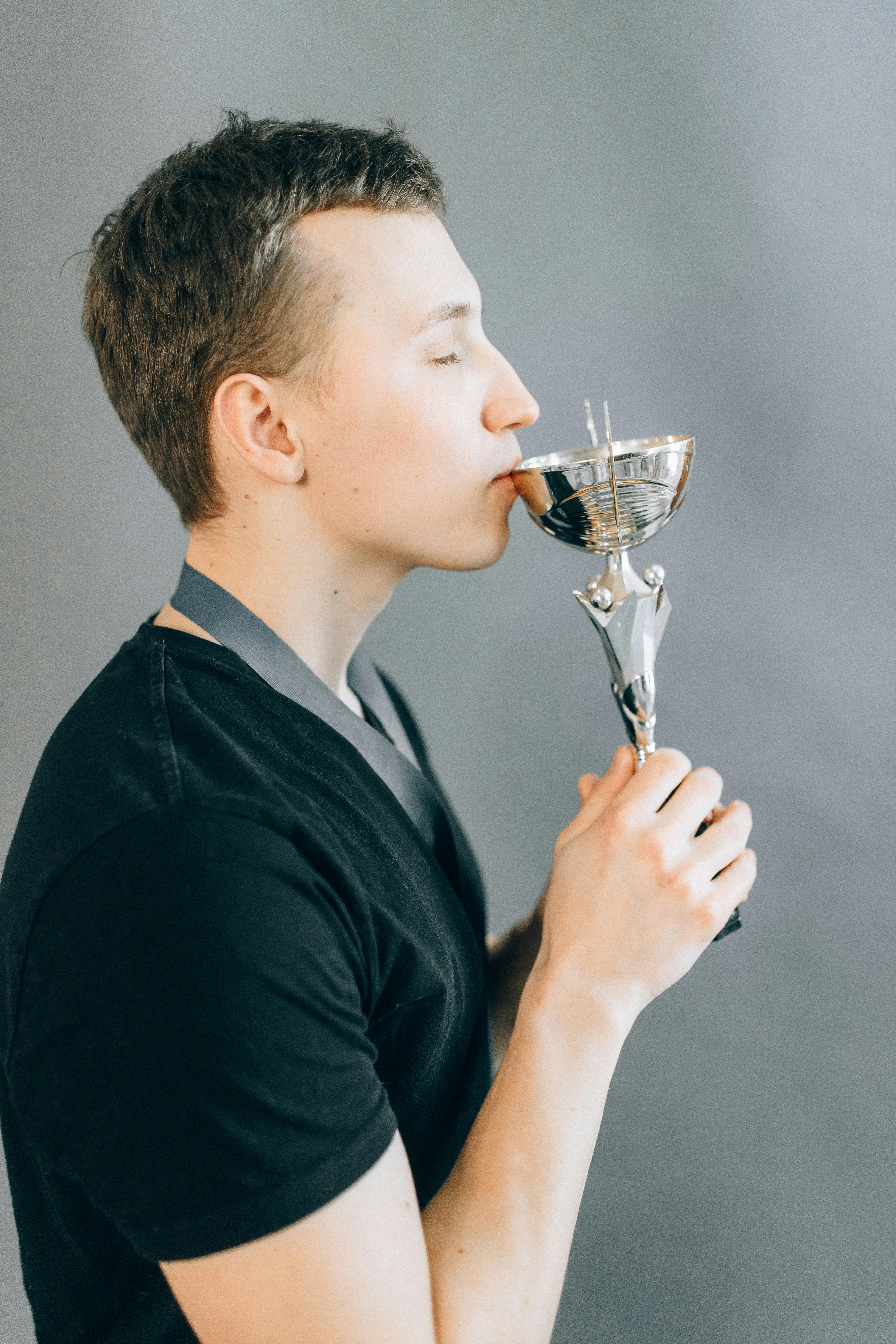 man in black shirt drinking water from clear wine glass