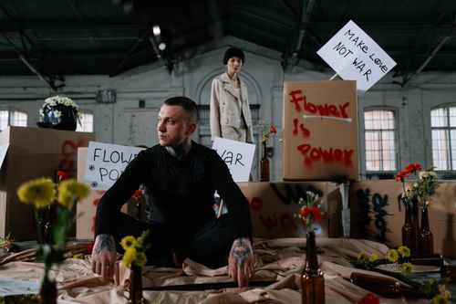 Free Individuals engage in a peaceful protest indoors with flower-themed slogans on signs. Stock Photo