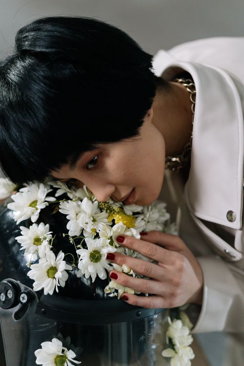 Free Asian woman gently rests on floral helmet, symbolizing peaceful protest. Stock Photo