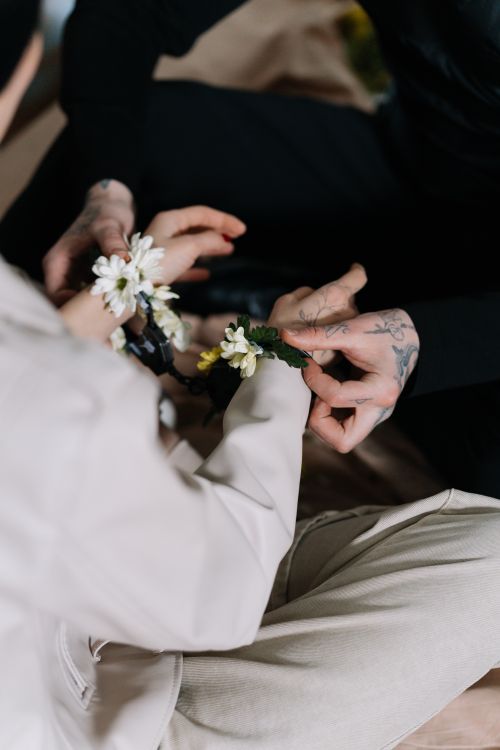 Free Close-up of two people with floral bracelets symbolizing peace and unity during a gentle interaction. Stock Photo