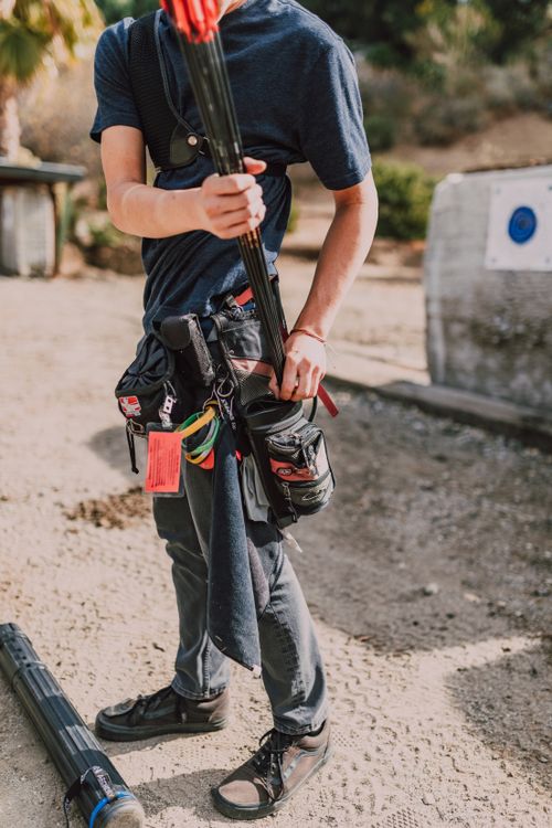 Free A young archer adjusts their gear in preparation for archery practice at an outdoor range. Stock Photo