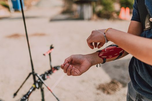 Close-up of a person adjusting an archery arm guard outdoors, showcasing archery preparation.