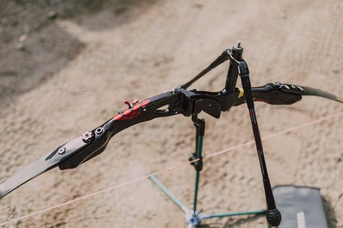 Free A close-up of a modern compound bow resting on a stand at an outdoor archery range. Stock Photo