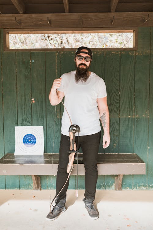 Bearded Man in a White Shirt Holding a Bow and Arrow