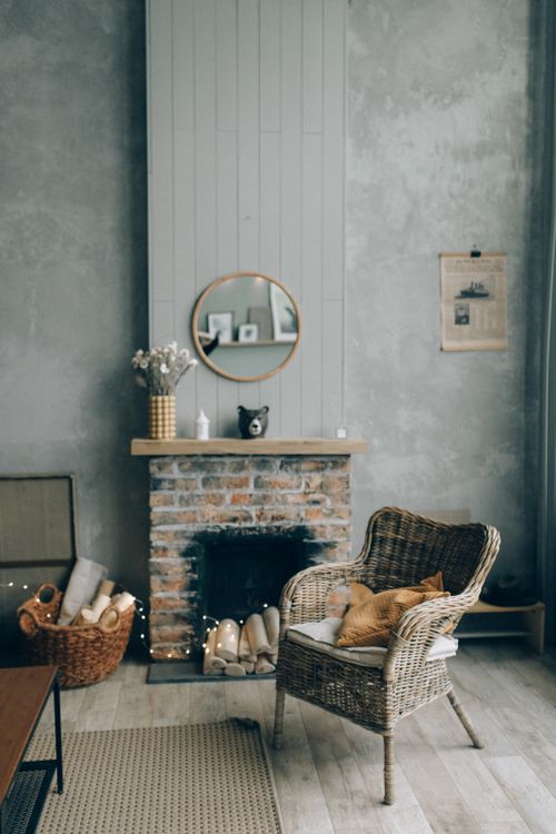 Free Charming interior of a rustic living room featuring a wicker chair, brick fireplace, and wooden decor. Stock Photo