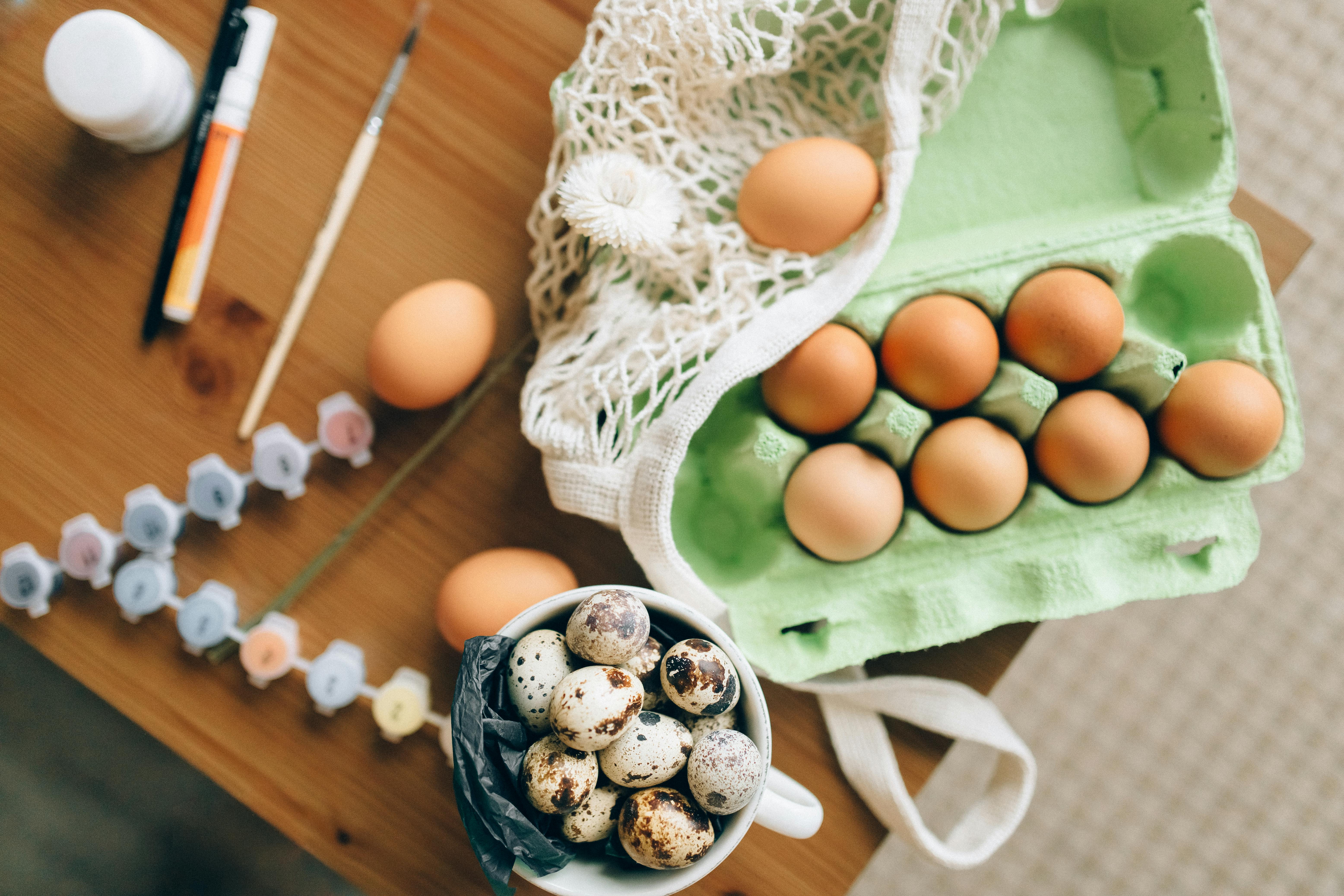 Artistic top view of chicken and quail eggs with painting supplies, perfect for food or Easter themes.