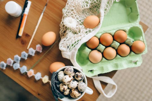 A Bowl of Quail Eggs Beside a Tray of Chicken Eggs on a Wooden Table