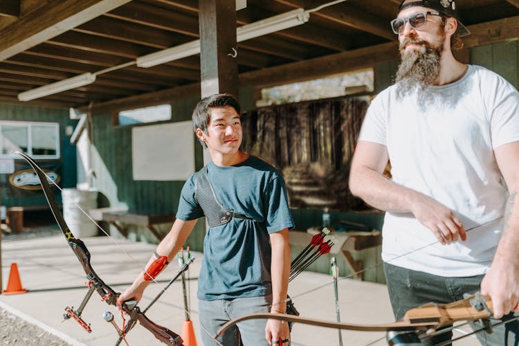 A Young Man Beside A Bearded Man Practicing Archery