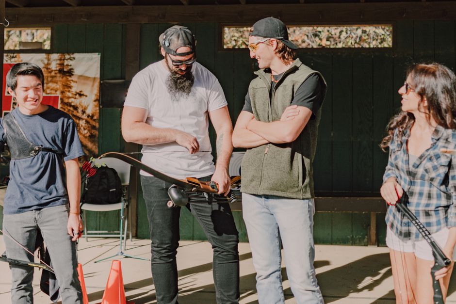 A group of adults engaging in archery practice outdoors, enjoying a sunny day.