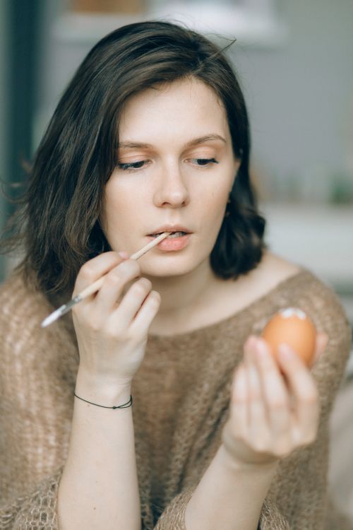 Free Young woman carefully painting an egg, symbolizing creativity during Easter. Stock Photo