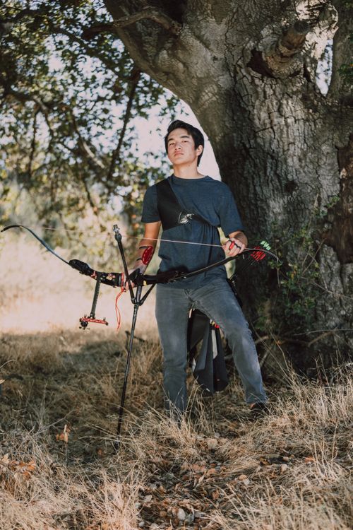 Free A young man stands with a compound bow in an autumn forest, preparing for archery practice. Stock Photo