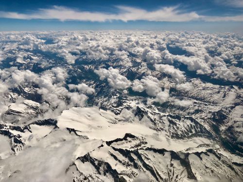 Free A breathtaking aerial perspective of a vast snowy mountain range under a blanket of clouds. Stock Photo