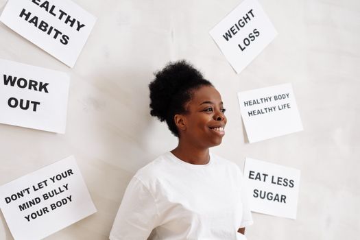 Portrait of a smiling woman surrounded by health motivation signs on a white background, promoting a healthy lifestyle.