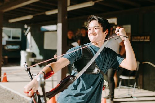 Free Young archer practicing with a bow and arrow, expressing joy and focus outdoors. Stock Photo