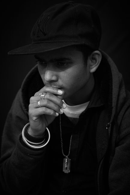 Black and white photo of a young man in a black hat, looking contemplative.