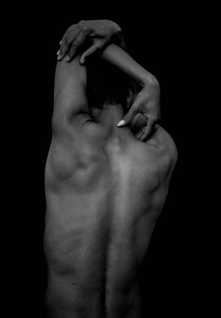 Monochrome image of a person stretching, showcasing muscular back.