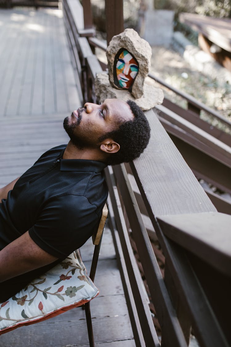 Man Looking Up While Resting Head On Balcony Rail 