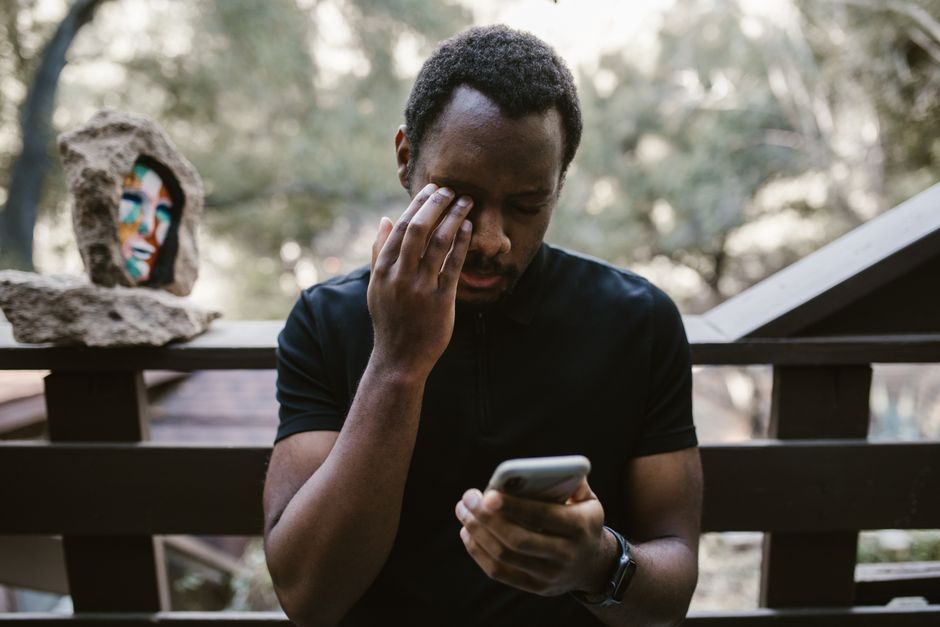 スマートフォンを持ちながら泣く男性