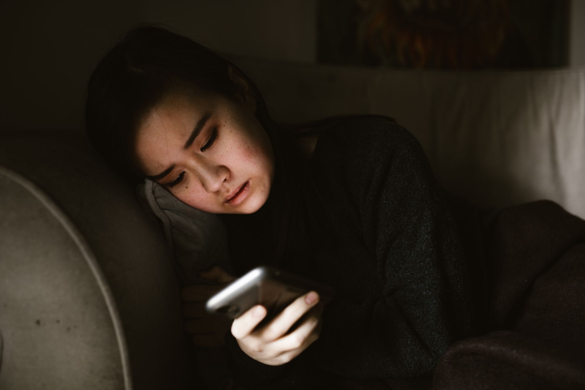 A woman on a sofa at home browsing on her phone in the evening, the moment a bio link actually gets tapped