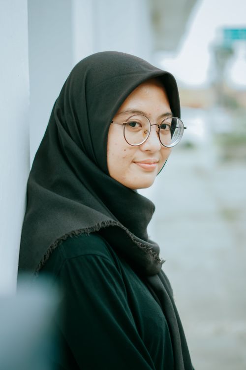 Free Young Muslim woman in hijab with glasses, outdoors in a serene setting. Stock Photo
