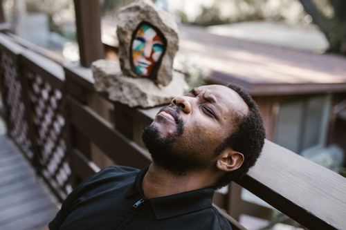 Free A thoughtful man with closed eyes leaning on a wooden deck, embracing a moment of calm outdoors. Stock Photo