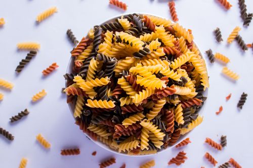 Free A vibrant flat lay of tricolor fusilli pasta in a white bowl, perfect for Italian cuisine themes. Stock Photo