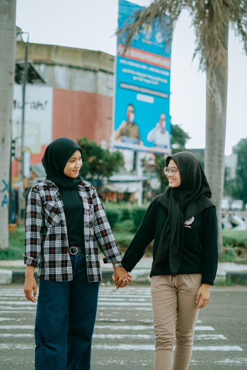 Free Two women in hijabs walking hand in hand on a street in Cirebon, Indonesia. Stock Photo