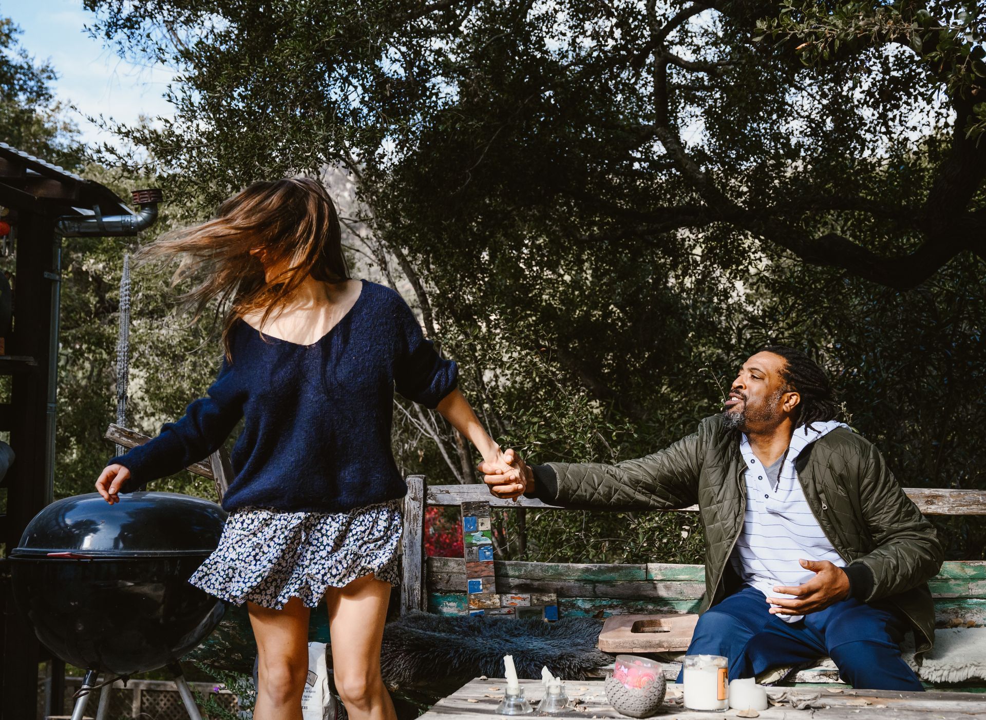 Friends enjoying leisure time outdoors with a barbecue grill and laughter.