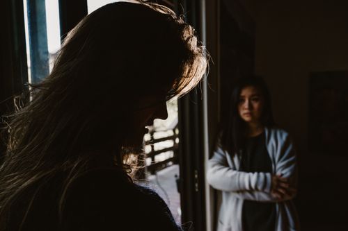 Free Two women facing a tense emotional exchange in a dimly lit room. Stock Photo