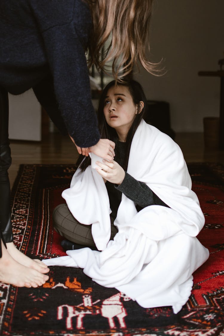 Sad Woman Sitting On Rug With White Blanket