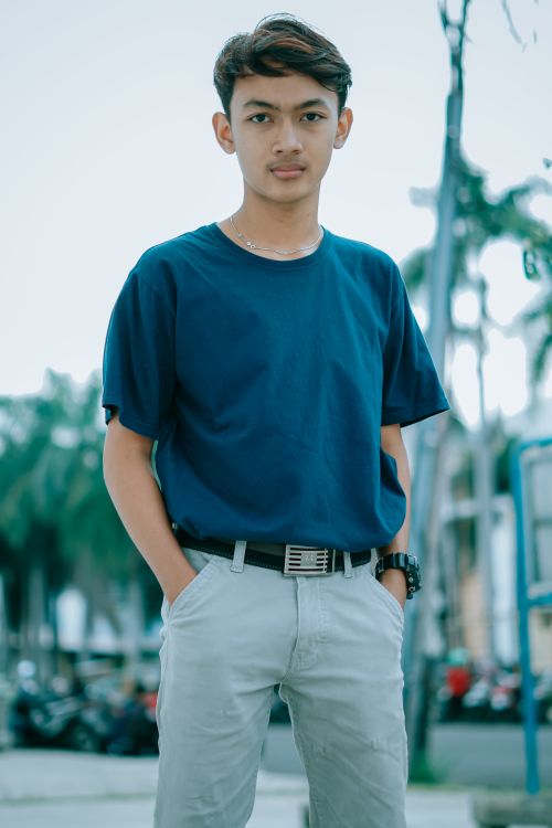 Free Casual portrait of a young man in a blue shirt with hands in pockets, outdoors. Stock Photo