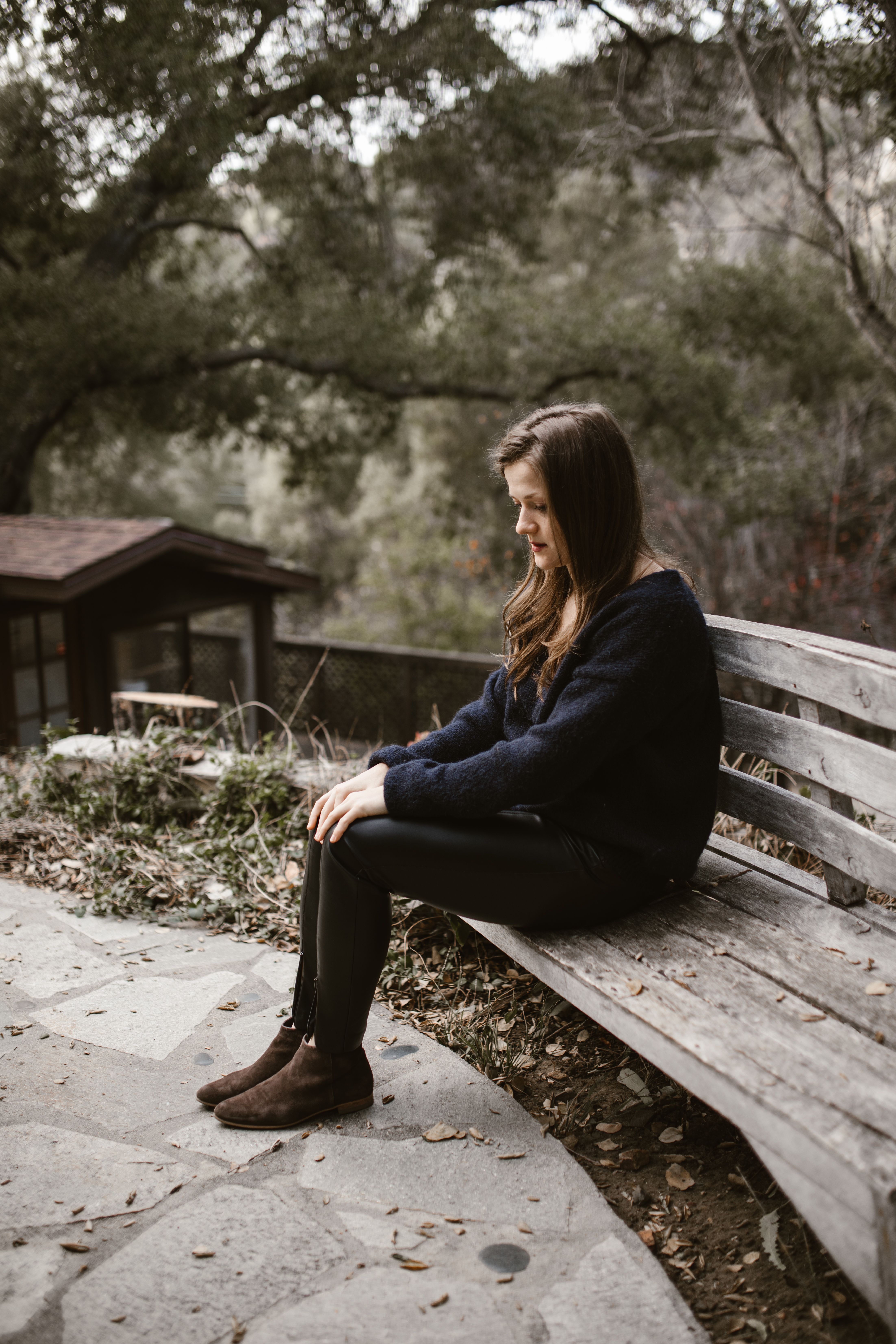 Woman in Black Sweater Sitting on Brown Wooden Bench · Free Stock Photo