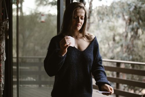 Free Woman holding papers standing on a balcony, contemplating. Stock Photo