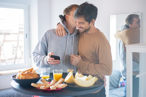 Free Photo of a Man in a Gray Hoodie Kissing a Man in a Brown Shirt Stock Photo