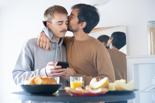 Free Photo of a Man in a Brown Shirt Kissing a Man in a Gray Hoodie Stock Photo