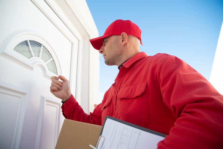 Man In Red Long Sleeve Shirt Knocking On White Wooden Door