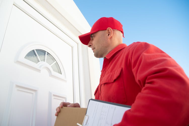 Man In Red Jacket Standing Beside White Door