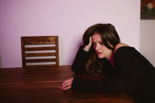 A Heartbroken Woman Leaning on the Table