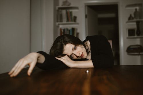 Free A Sad Woman Resting Her Head on a Wooden Table Stock Photo