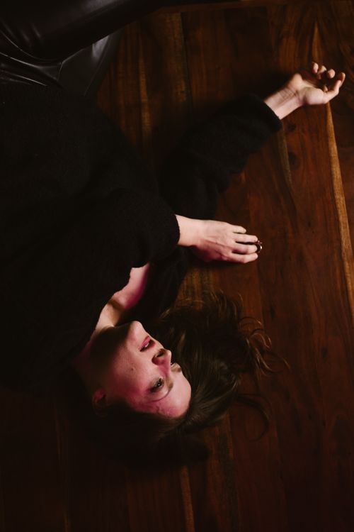 Free Contemplative woman in dark clothing resting on wooden floor, evoking emotions of introspection and calm. Stock Photo