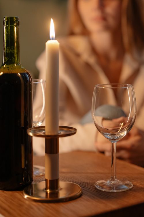 Free Cozy indoor table setup with a bottle of wine, glasses, and candlelight for a romantic evening. Stock Photo