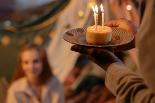 A close-up of a lit birthday cake with candles, capturing a warm indoor celebration feel.