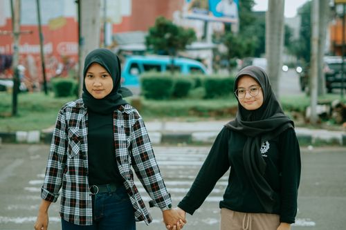 Free Two women in hijabs holding hands on a street in Cirebon, Indonesia, symbolizing friendship and unity. Stock Photo