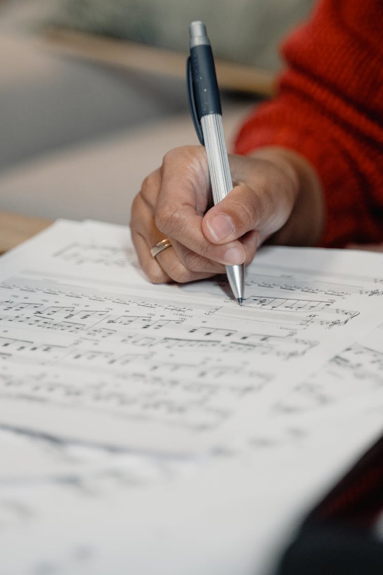 A Person Writing On A Sheet Music 