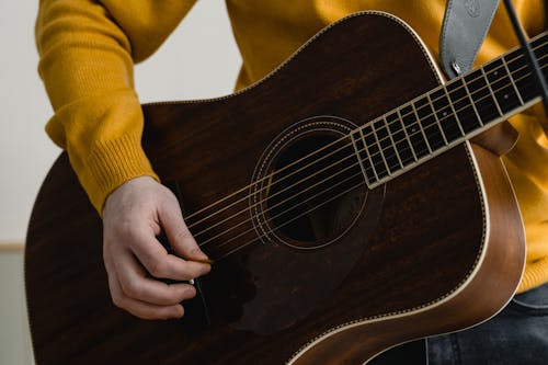Close-Up Photo of a Person Playing a Brown Acoustic Guitar