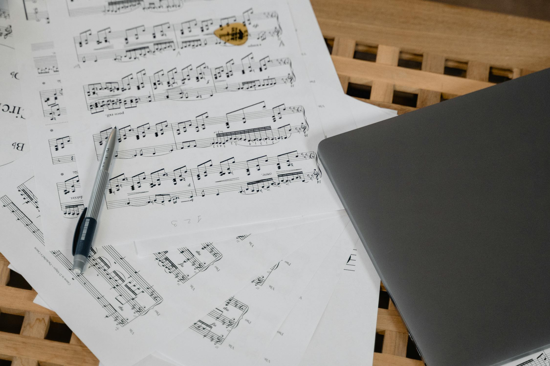 Laptop and Music Sheets on Wooden Surface · Free Stock Photo
