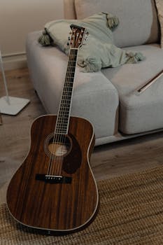 Acoustic guitar on a rug in a cozy living room setting with a sofa.